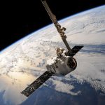 Satélite sobrevoa a Terra, com nuvens e o espaço ao fundo.