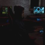 Profissional analisa dados em vários monitores em um ambiente de operações de cibersegurança.
