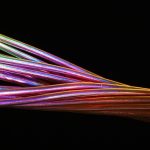 Cabos de fibra óptica coloridos contra um fundo escuro.