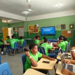 Grupo de estudantes reunido em sala de aula, usando laptops durante uma atividade acadêmica.