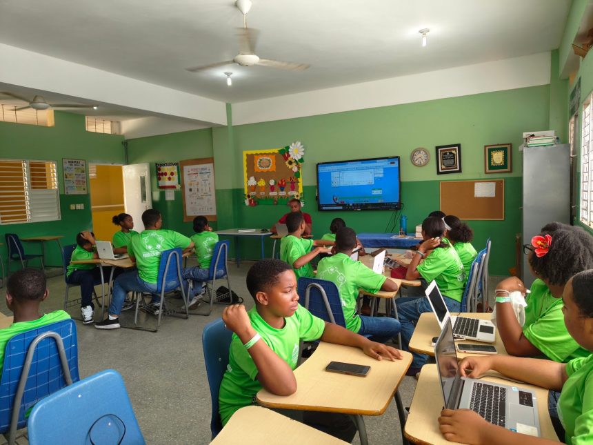 Grupo de estudantes reunido em sala de aula, usando laptops durante uma atividade acadêmica.