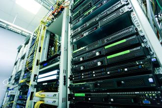 Rack de servidores em um data center, com cabos de rede e componentes de hardware visíveis.
