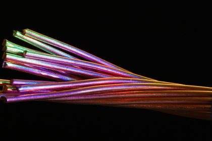 Cabos de fibra óptica coloridos contra um fundo escuro.