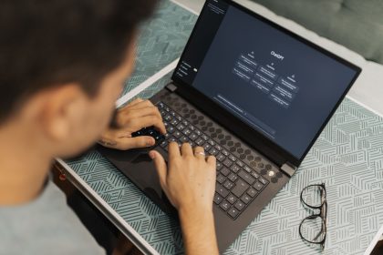 Profissional de óculos trabalha em um laptop com uma interface de inteligência artificial aberta na tela.