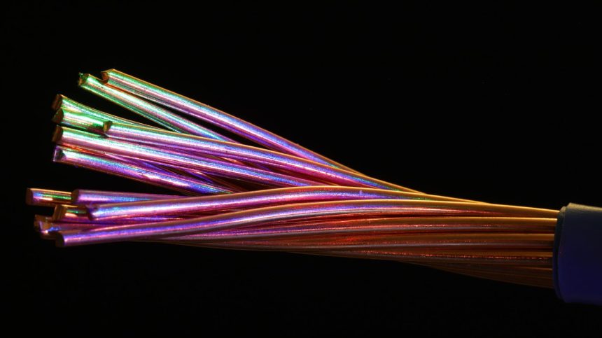 Cabos de fibra óptica coloridos contra um fundo escuro.