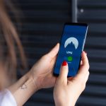 Close das mãos de uma mulher usando um aplicativo de segurança digital no celular.