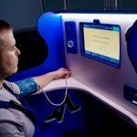 Homem mede a pressão arterial em um monitor digital instalado em um quiosque de telemedicina.