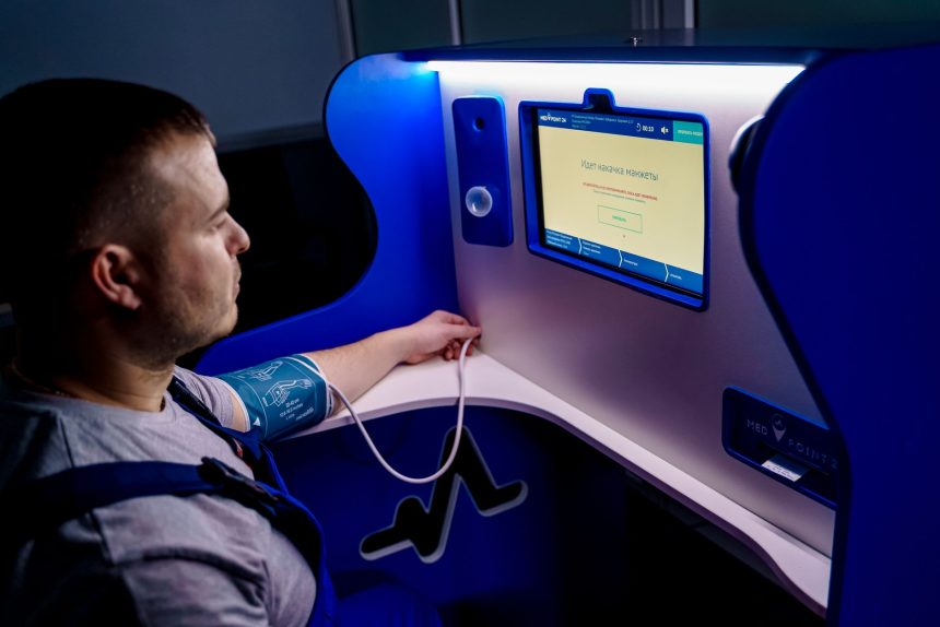 Homem mede a pressão arterial em um monitor digital instalado em um quiosque de telemedicina.