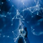 Mão robótica diante de uma rede digital azul, em uma representação conceitual de inteligência artificial e sistemas autônomos.
